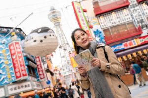 female tourist standing in the middle of the street, holding a map and finding the right way to go
